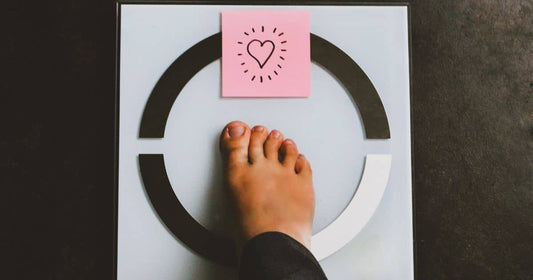 Fuß auf Waage mit Herzsymbol bei Gewichtsabnahme-Ziel